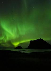 Eine Aurora im Himmel über einem Feld in der Unterkunft Haukland Panorama Lofoten in Offersøya