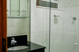 a bathroom with a sink and a glass shower at Hotel Beirut in Aparecida