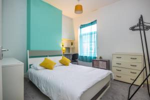 a bedroom with a white bed with yellow pillows at 2Bed Mid Terrace Close To Station in Stoke on Trent