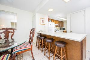 Una cocina con una barra con taburetes y una mesa. en Driftwood Towers 5E condo, en Gulf Shores