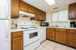 Una cocina con electrodomésticos blancos y gabinetes de madera. en Driftwood Towers 5E condo, en Gulf Shores