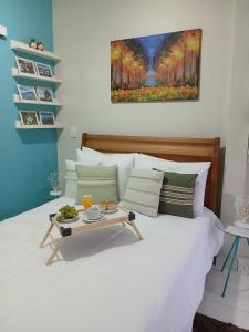 a white bed with a tray of food on it at Hospedagem Quarto Chic centro Cunha in Cunha