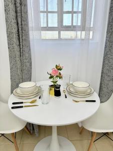 NarokにあるKoshy Cosy Homesの白いテーブルと皿と花