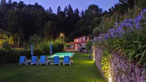 a backyard with a pool and chairs and a wall at Casa do Ribeiro in Sever do Vouga