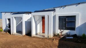 Ga-MothapoにあるVilla Tlhago Lodgeの側面に赤いドアがある白い家