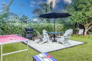 a ping pong table and chairs with an umbrella at "LuxuryCrest , King Bed, BBQ & Backyard Games, Near Ocho Rios" in Ocho Rios