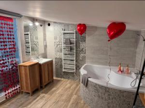 a bathroom with a tub and two red heart balloons at Dawna Mleczarnia Apartamenty FAMILIJNY in Nowa Ruda +18 photos