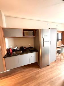 a kitchen with a stainless steel refrigerator and a table at Flat Premiun Vila Madalena in São Paulo