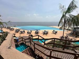 a swimming pool with tables and chairs on a beach at Flat vista Rio in Manaus