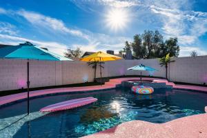 a swimming pool with two umbrellas and a swimming pool at Dollhouse Daydream! Barbie-Inspired Home in Peoria