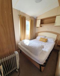 Un dormitorio con una gran cama blanca con ventana. en Pet Friendly 3 Bed Static Caravan in Clarach Bay Spacious and Cozy Stay, en Aberystwyth
