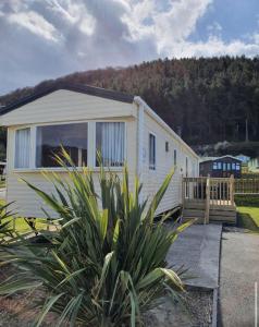 Casa blanca pequeña con porche y valla en Pet Friendly 3 Bed Static Caravan in Clarach Bay Spacious and Cozy Stay, en Aberystwyth