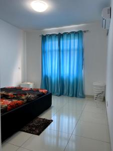 a bedroom with a bed and a blue curtain at Apartamento Condomínio Vila Flor in Viana