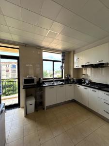 a large kitchen with white cabinets and a large window at Apartamento Condomínio Vila Flor in Viana