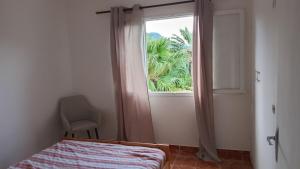 a bedroom with a window and a bed and a chair at Appartement F4 Kone centre Tel 7O 55 O8 in Koné