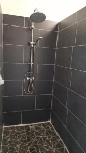 a black tiled shower with a shower head at Appartement F4 Kone centre Tel 7O 55 O8 in Koné +17 photos