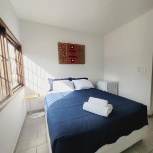 a bedroom with a blue bed with two white pillows at Espaço IN 1 Suite Brooklin mobiliado in Sao Paulo