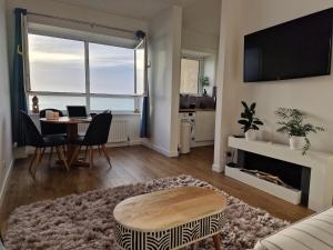 a living room with a couch and a table and a television at Flat by the sea with great view in Kinghorn