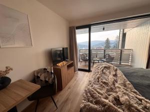 a bedroom with a bed and a television and a balcony at Corso Harrachov Panorama in Harrachov