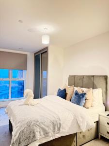 a bedroom with a large white bed with blue pillows at Skyline View Apartments - City Lights & Skyline Heights in Barking
