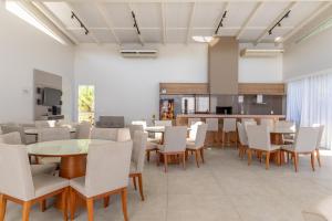 ein Esszimmer mit weißen Tischen und Stühlen in der Unterkunft Casa 4 Suites Garopaba, Rosa Internacional - Surfland in Garopaba