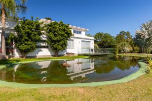 ein Haus mit einem Teich davor in der Unterkunft Casa 4 Suites Garopaba, Rosa Internacional - Surfland in Garopaba