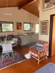 a living room with a table and chairs and a kitchen at Whangapoua Paradise in Whangapoua