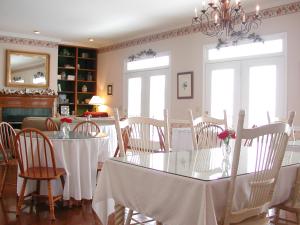 a dining room with two tables and chairs with flowers on them at The Garden Inn Bed & Breakfast at Bee Rock in Monterey