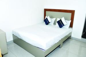 a white bed with blue and white pillows on it at Hotel J K and Restaurant Couple Friendly in Morbi