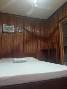 a bedroom with a bed with a wooden wall at Naramalan Inn in San Vicente +1 photo
