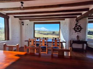 a dining room with a table and chairs and a large window at Cotopaxi Lodge in Hacienda Porvenir