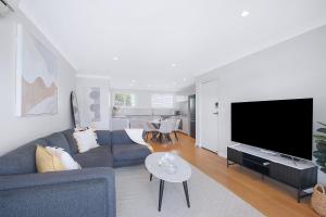 a living room with a couch and a flat screen tv at Greenslopes Cityview Haven in Brisbane
