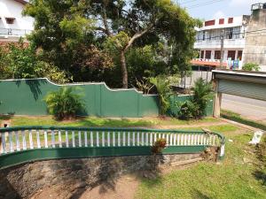 a green bench sitting in the grass next to a fence at Heritage Bungalow Hikkaduwa in Hikkaduwa