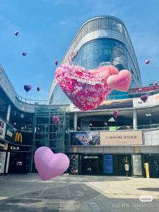 a bunch of heart balloons hanging in front of a building at 宜尚酒店 日月广场骑楼老街店 in Haikou