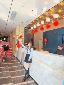 a woman standing at a counter in a restaurant at 宜尚酒店 日月广场骑楼老街店 in Haikou