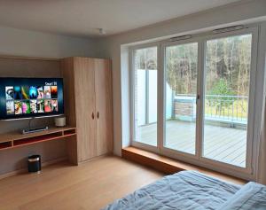 - une chambre avec une porte coulissante en verre et une télévision dans l'établissement Residenz-Am-Wald-Nr-2-0, à Sankt Peter-Ording