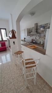 a white kitchen with white chairs and a counter at Dimora Scandereberg Felline in Felline