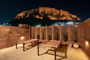 a patio with a table and benches in front of a mountain at Aakash Heritage Haveli in Jodhpur