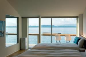 a bedroom with a large bed and two chairs at Umikara , Obama Ocean Suite in Unzen