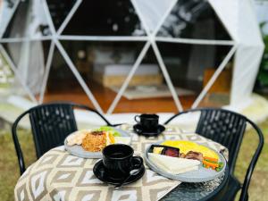 a table with two plates of food and cups on it at De'Ra Hills Camp Kintamani in Kintamani