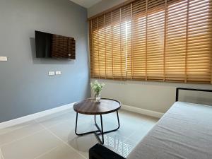 a room with a table and a bed and a television at Cha V Place Buriram - ชาวีเพลส บุรีรัมย์ in Ban Yang