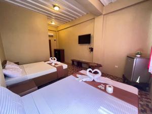 a hotel room with two beds and a tv at Oceanfront Beach Resort in Siquijor