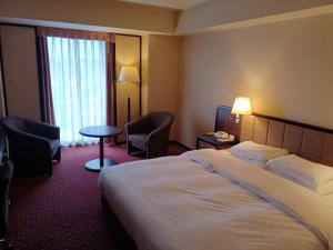 a hotel room with a bed and chairs and a window at ANA Crowne Plaza Hotel Kyoto by IHG in Kyoto