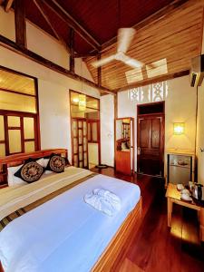a bedroom with a large white bed and wooden floors at Ireenkevin guesthouse in Luang Prabang