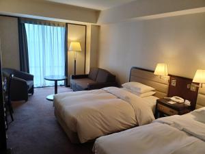 a hotel room with two beds and a chair at ANA Crowne Plaza Hotel Kyoto by IHG in Kyoto