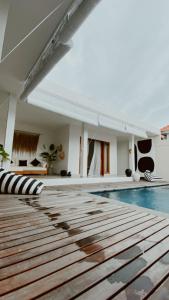 a swimming pool with a wooden floor and a building at Villa Hope Bali in Kerobokan +13 photos