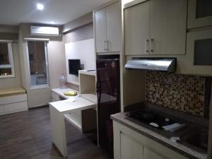 a kitchen with white cabinets and a black refrigerator at For rent or sale Puncak Kertajaya apartment in Surabaya