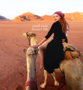 a woman is riding a camel in the desert at Wadi Rum Desert Life in Wadi Rum