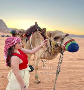 ワディ・ラムにあるWadi Rum Desert Lifeの砂漠のラクダの横に立つ少女