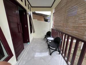 a balcony with two chairs and a table and a door at Parkside nest-studio 3 in Kuta Lombok